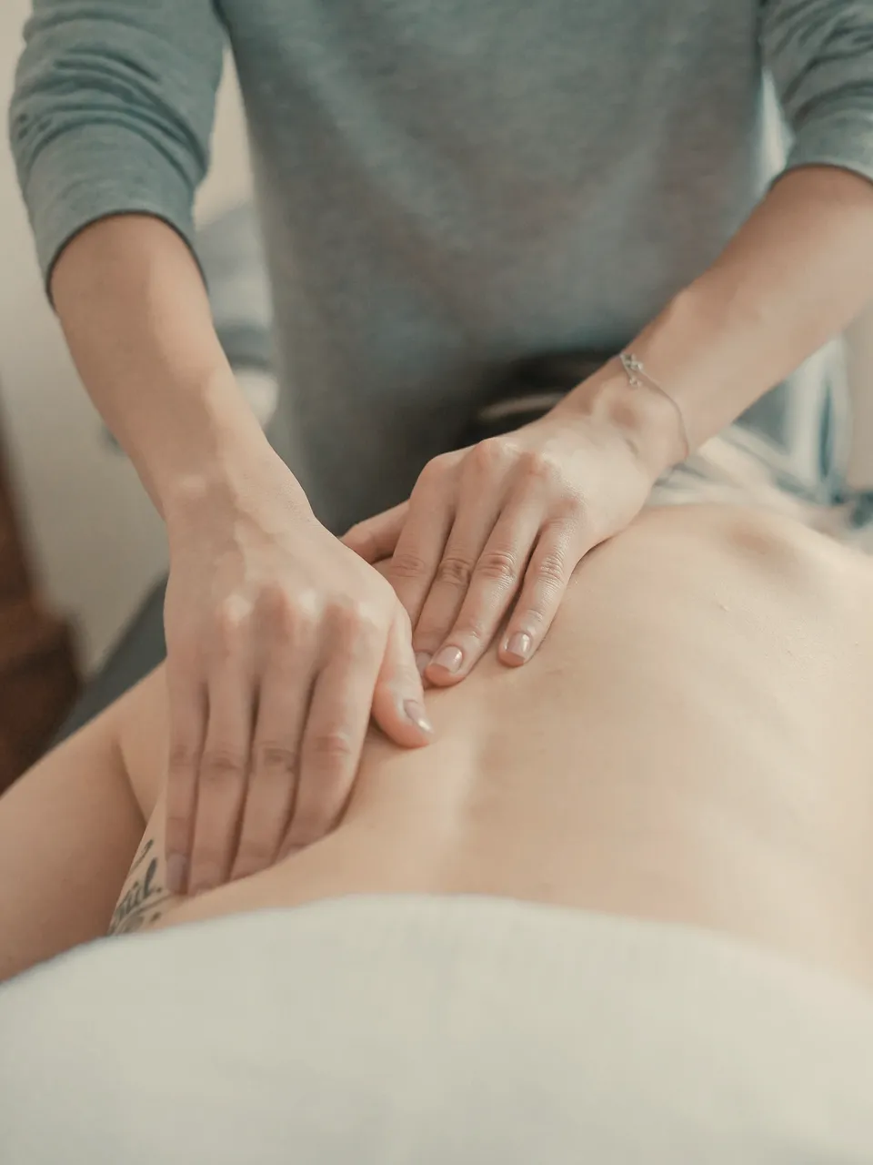 Terapeuta a massajar as costas de uma cliente com as duas mãos